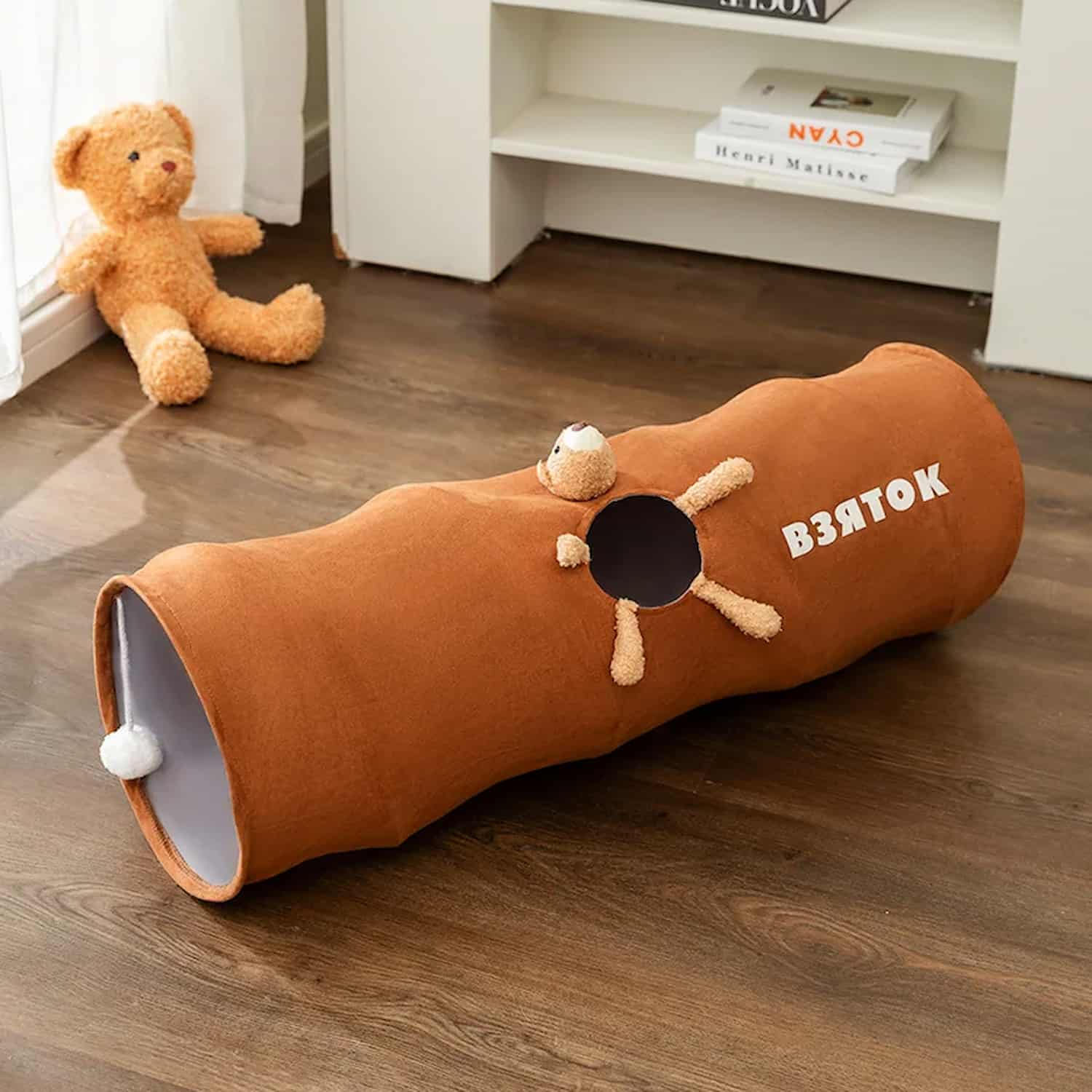 Foldable velvet cat play tunnel with plush bear peephole opening, interior hanging ball, moisture-absorbing lining, available in 31 and 47 inch lengths